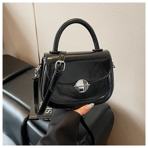 Dettaglio della borsa a sella in pelle cerata nera con pomello in metallo e manico chic