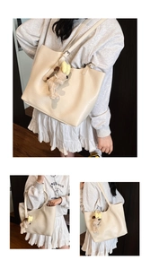 Close-up of minimalist cream tote bag featuring a cute dog plush charm and soft leather texture