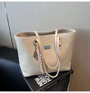 Detail of minimalist beige woven tote bag with textured surface and stylish blue label