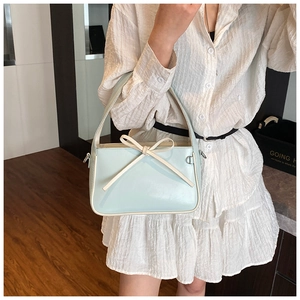 Détail du sac à main en cuir verni bleu menthe avec un élégant nœud décoratif blanc crème