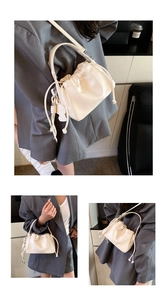 Close-up of pleated cream bucket bag with drawstring detail and pebble grain texture