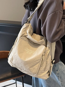 Large beige travel tote bag with slogans shown on a model in a modern interior