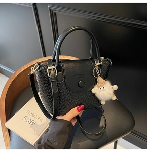 Détail d'un sac seau noir à texture tressée avec un charmant monstre en peluche