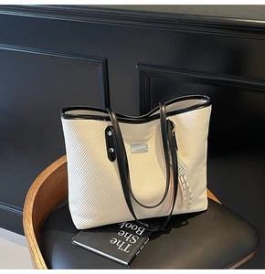 Detail of the woven texture and black leather strap on a minimalist cream tote bag