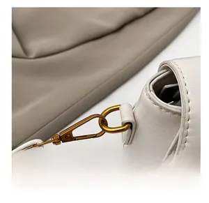 Vue macro des crochets en métal doré et des détails de couture sur un sac en cuir blanc