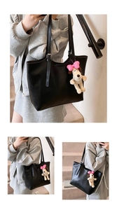 Detail view of a black tote bag with a cute puppy pendant on a minimalist background