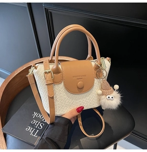 Détail d'un sac à main motif crocodile avec breloque en peluche sur fauteuil en cuir