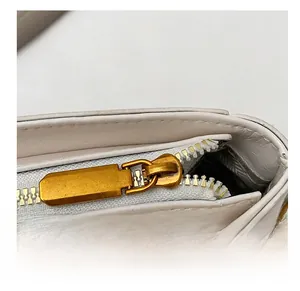 Détail de la fermeture éclair en métal doré sur un sac à main en cuir blanc crème élégant