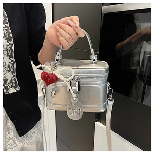 Detail view of silver box handbag with pearl bow charm and red heart pendant