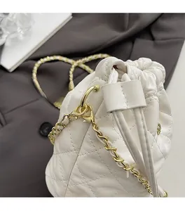 Détail du sac seau blanc matelassé avec bandoulière chaîne dorée et finitions métalliques