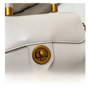 Vue macro d'un sac à main en cuir blanc avec un fermoir rotatif doré poli classique