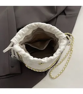 Vue de dessus d'un sac seau blanc matelassé avec cordon de serrage et bandoulière chaîne