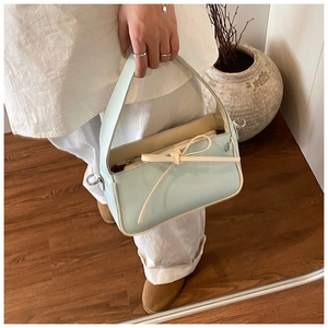 Détail du sac seau vert menthe avec nœud et passepoil contrasté sur sol en bois