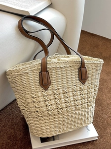 Straw woven tote bag with brown leather handles and inner drawstring lining for beach travel