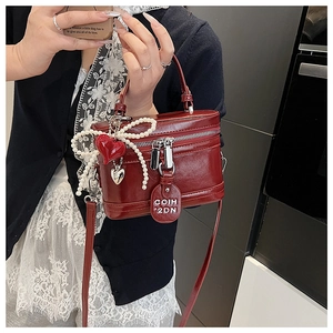 Detail of red vintage box bag featuring pearl bow and heart charms for women