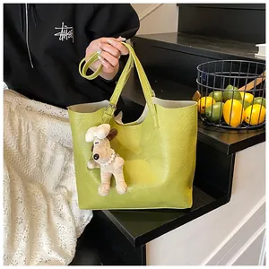 Close-up of lime green tote bag with lychee texture and cute plush puppy charm