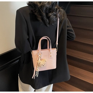 Detail of light pink woven bucket bag with fashion text and cute plush bear charm