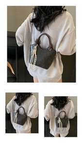 Détail du sac seau gris mat avec poignée anneau marron et breloque à pompon coloré