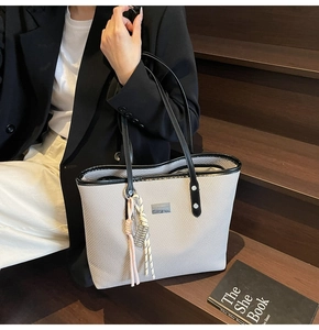 Detail of the woven texture and colorblock tassel on the large grey tote bag