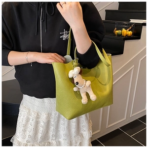 Detail of light green tote bag with wrinkled leather texture and plush dog pendant