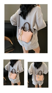 Détail du sac seau en cuir rose avec poignées marron et pompon tissé décoratif