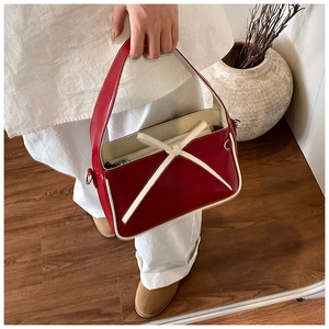 Détail du sac seau bicolore rouge et crème avec lanières en cuir verni contrastées