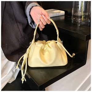 Detailed macro of cream leather texture and drawstring closure on a pleated handbag