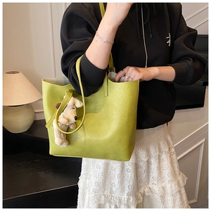 Detailed avocado green tote bag with fine leather texture and cute plush dog charm