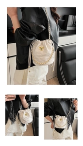 Détails du sac seau matelassé blanc avec emblème de chien doré et bandoulière chaîne