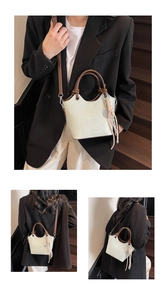 Détail du sac seau beige avec anses rondes marron foncé et pendentif à pompon