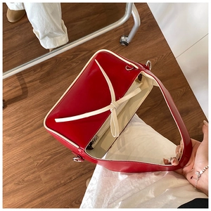 Vue détaillée du sac seau en cuir rouge avec un nœud crème et une fermeture éclair en métal