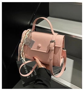 Pink minimalist crossbody bag with metal tennis racket charm and silk scarf detail