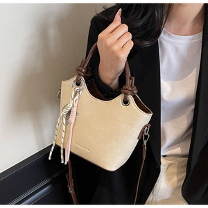 Détail du sac seau beige avec poignée nouée marron et breloque en corde tissée