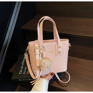 Detailed texture of pink woven bucket bag with detachable strap and plush bear charm