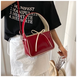 Détail du sac seau en cuir verni rouge avec nœud crème et bordure contrastée