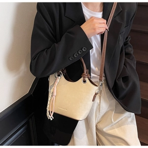 Détail du sac seau minimaliste avec bandoulière et pendentif à pompon tissé élégant