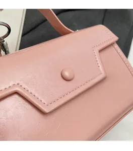 Detailed close-up of pink faux leather bag showing lychee grain texture and stitching