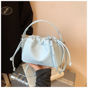 Detail of light blue lychee pattern handbag with drawstring pleats and chic handle