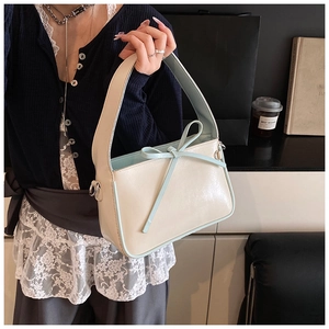 Détail d'un sac seau blanc crème avec liseré bleu clair et nœud décoratif élégant