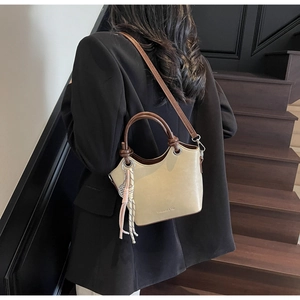 Sac seau crème avec poignée marron contrastée et breloque tressée colorée