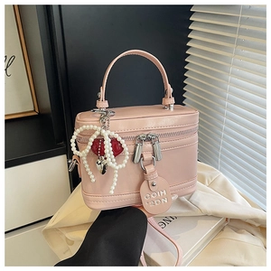 Detailed shot of pink box bag featuring a pearl bow charm and elegant double zippers