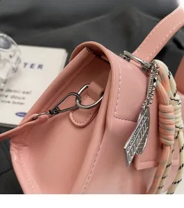Close-up of pink handbag side with silver metal lobster clasp and decorative leaf charm