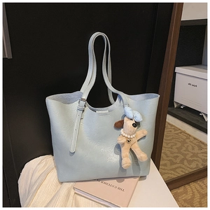 Detail of light blue faux leather tote bag with fluffy puppy pendant and silver buckle