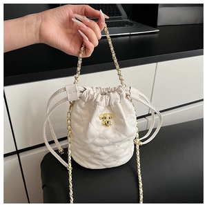 Détail du motif matelassé à losanges et de l'emblème de chien doré sur le sac seau beige