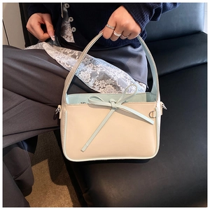 Détail d'un sac seau jaune pastel avec un nœud bleu et une bordure de poignée