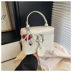 Detailed shot of white box bag featuring red hearts, pearl chain and silver zip