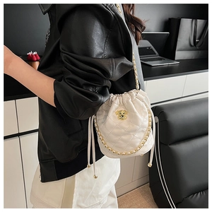 Détail du sac seau blanc matelassé avec emblème de chien doré et bandoulière en chaîne