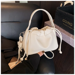 Detailed view of cream leather pleats and drawstring tassel on a textured crossbody bag
