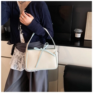 Détail du sac seau blanc crème avec un nœud bleu clair et des finitions argentées