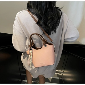 Détail du sac seau rose orangé avec logo embossé et finitions de poignées torsadées